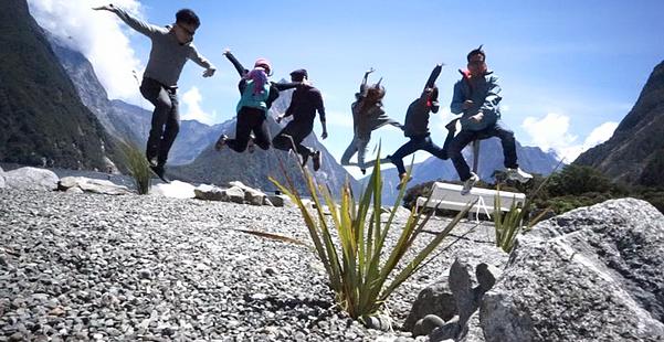 Group jumpshots with the view of Milford Sound.