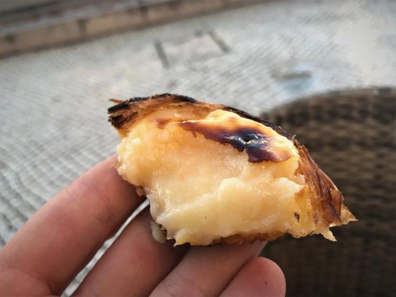 A bite off the crusty egg tart with soft custard inside. Hungry already! pastel de nata