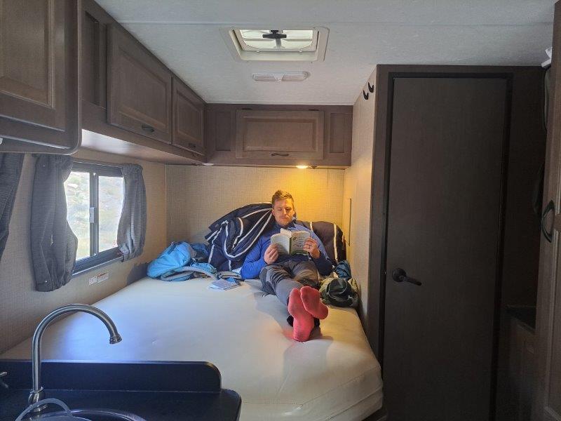 relaxing with a book on a bed inside the rv campervan
