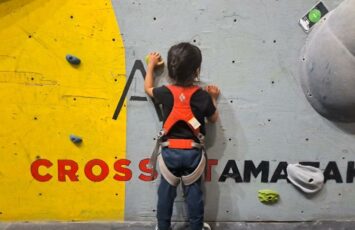 child ready to climb at a gym with safety harness on