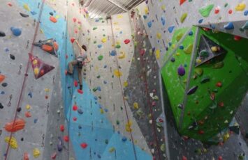 lady in grey climbing up gym wall
