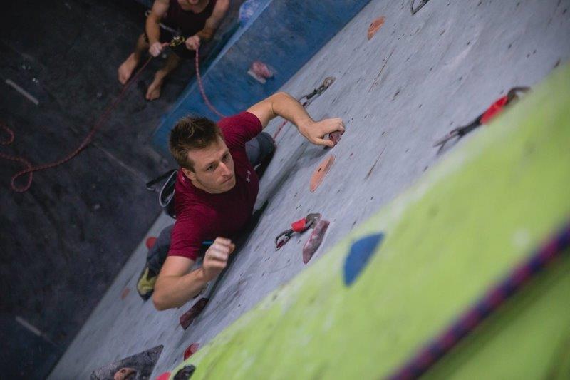 man in red climbing gym wall