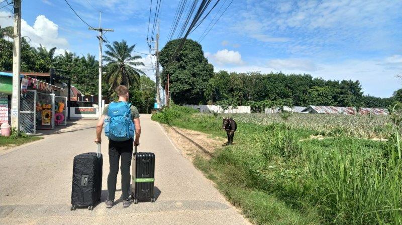 man with two black luggagues on a sandy road