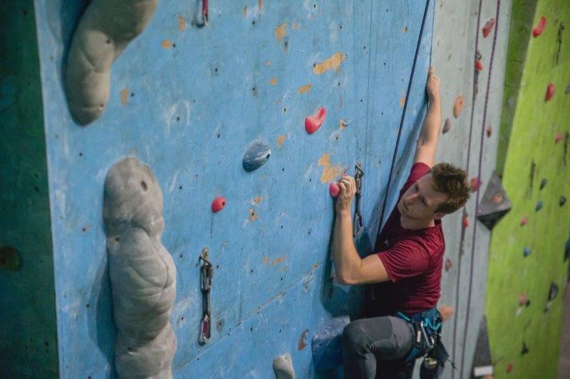 male climber in red looking focused in climbing gym