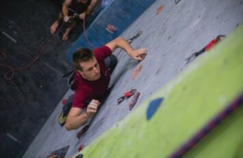 man climber in red shirt about to grap next rock hold