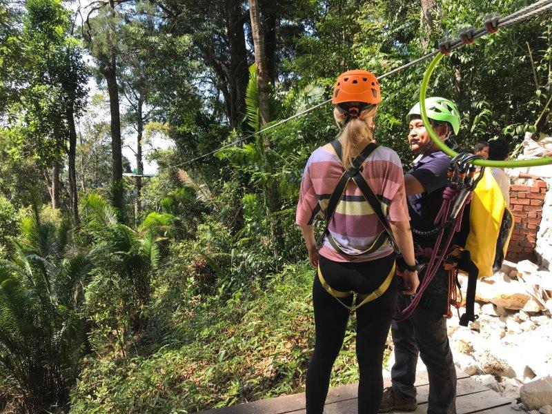 pair in safety harness at rainforest trail getting ready