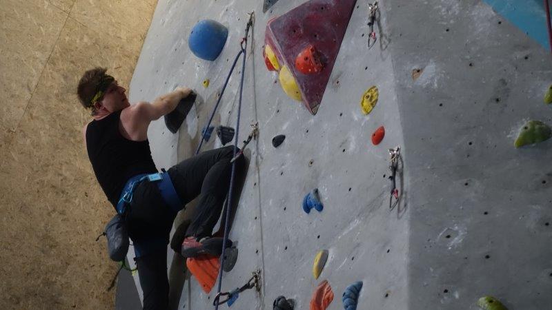rock climber in black along gym wall