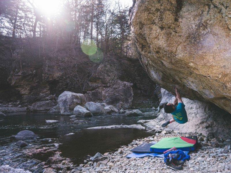 Climbing steep inclined rock from ground with crash mat