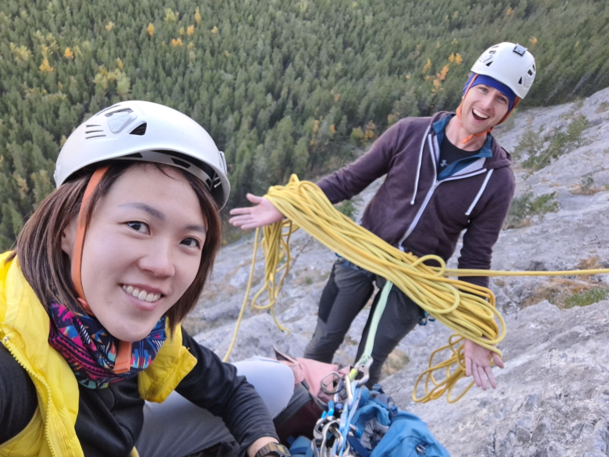 safety gear white helmets and yellow rock climbing ropes Petzl vs Black Diamond - showing off the climbing gear midclimb at Banff National Park